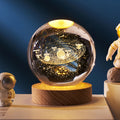 Glowing crystal ball with a carved solar system on a wooden base