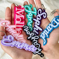 Colorful acrylic name keychains held in a hand