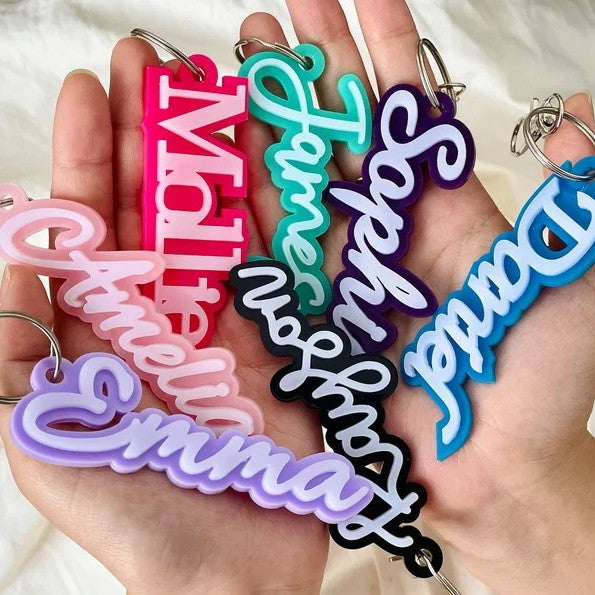 Colorful acrylic name keychains held in a hand