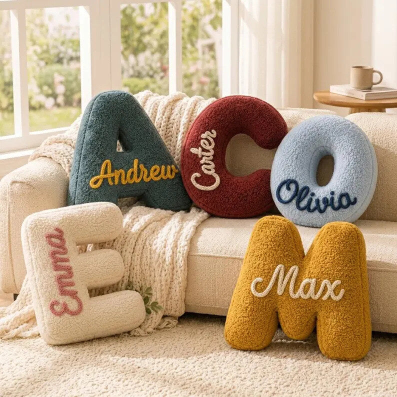 Plush letter pillows embroidered with children's names on a sofa