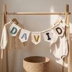 Canvas flag banner spelling DAVID in multicolor yarn letters on a clothes rack