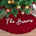 Personalized Christmas tree skirt in red knit with The Browns embroidered in white script under a decorated tree