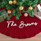 Personalized Christmas tree skirt in red knit with The Browns embroidered in white script under a decorated tree