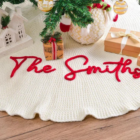 Red script family name stitched along the scalloped edge of a cream tree skirt