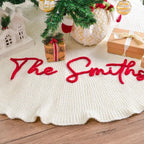 Red script family name stitched along the scalloped edge of a cream tree skirt