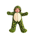 Baby wearing a green plush turtle onesie with a hood