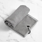 Rolled gray waffle microfiber golf towel with a metal carabiner clip