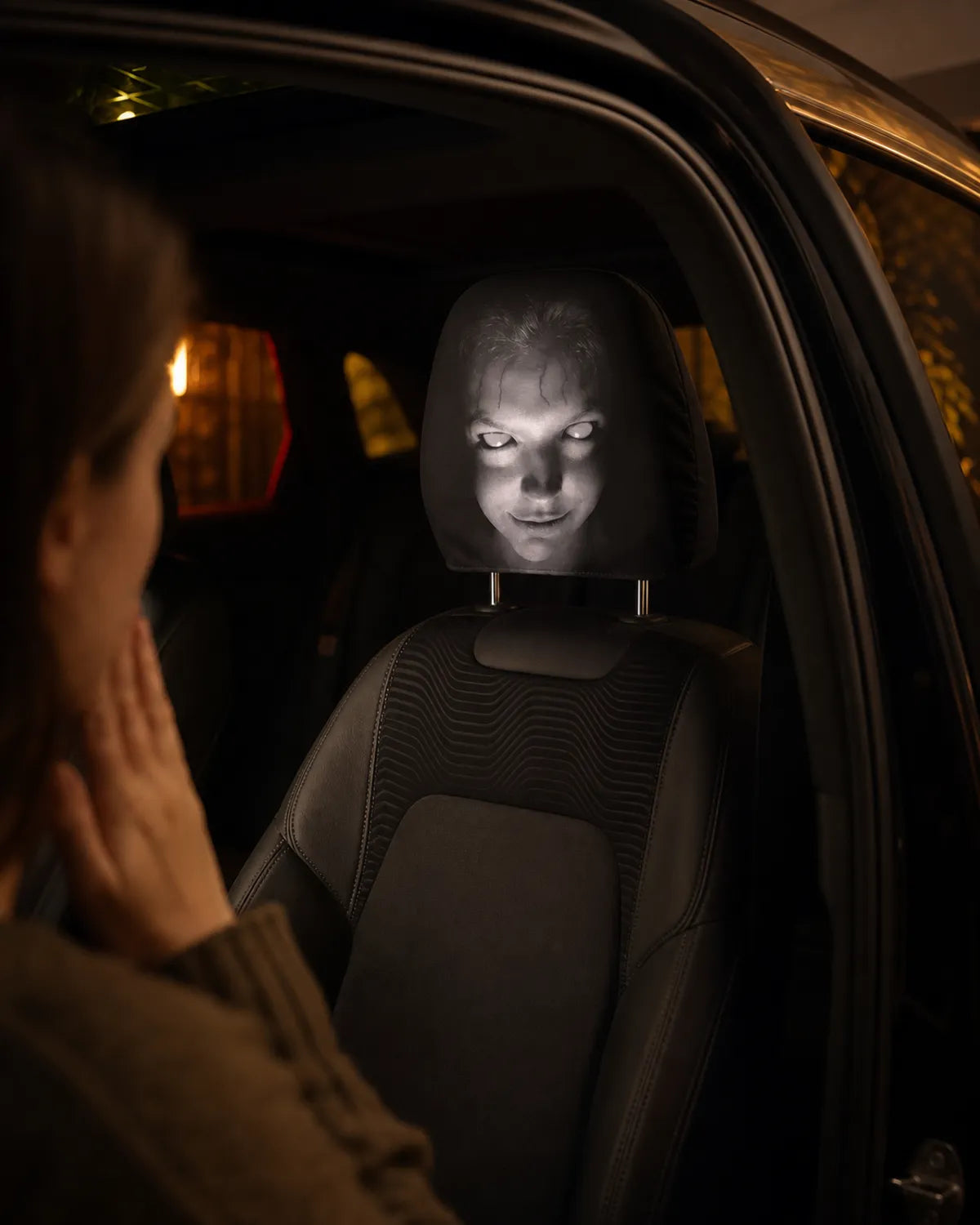 Passenger reacting to a scary face cover on a car headrest